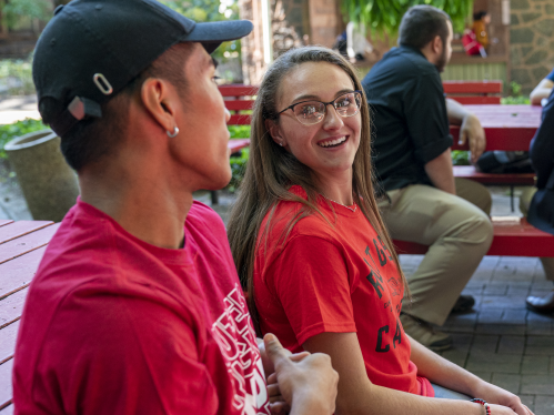 Students talking at picnic table in front of the Admissions Building.